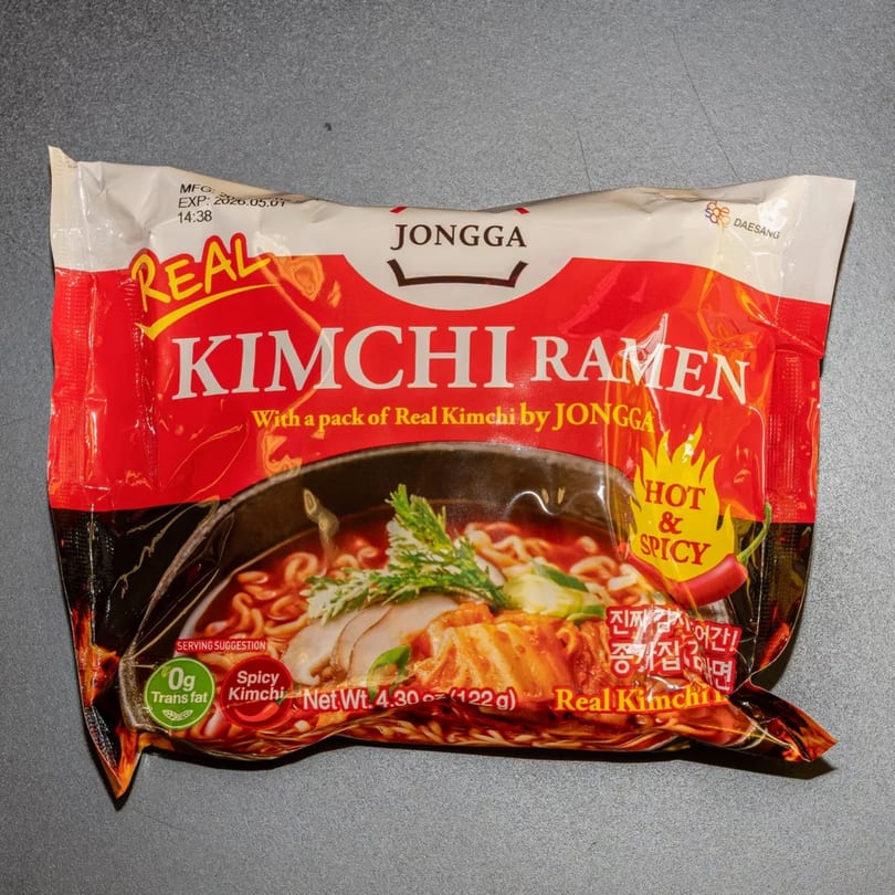 A red and white package of Jongga Real Kimchi Ramen, with a serving suggestion of ramen in a bowl.