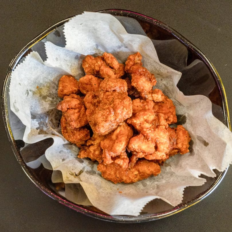 A bowl of crispy Korean fried chicken bites, served on white parchment paper.