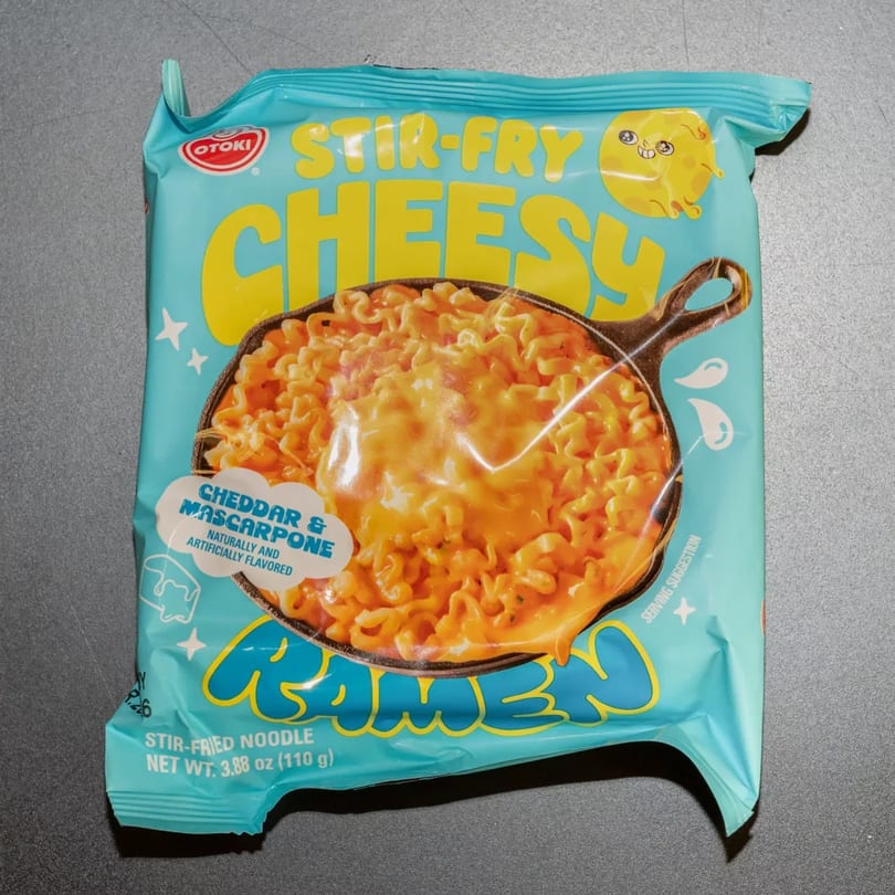 Otogi Stir-Fry Cheesy Ramen package, featuring cheesy noodles in a skillet on a light blue background.